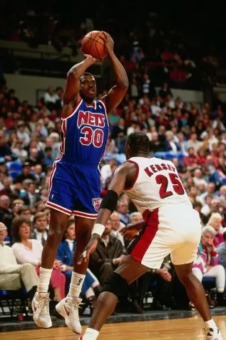 A basketball player is in the air with his arm raised.