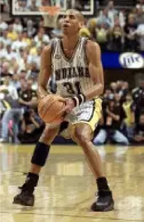 A man holding a basketball on top of a court.