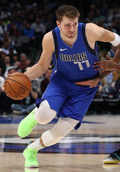 A man in blue and white basketball uniform dribbling.