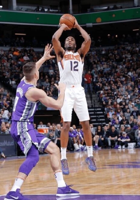 A basketball player is in the air with his foot on the ground.