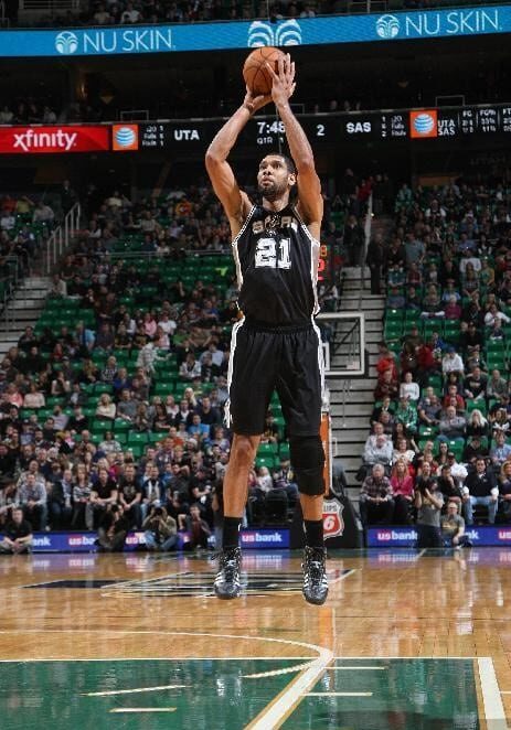 A man in black and white basketball uniform holding a ball.