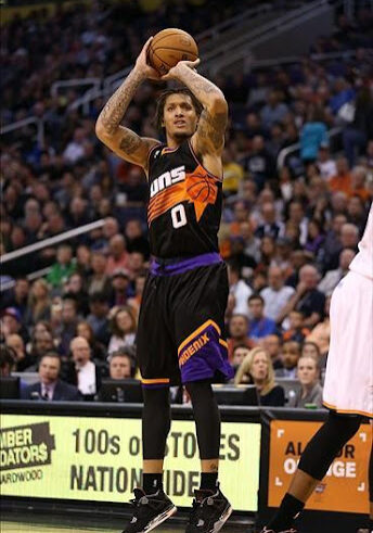 A man in black and orange basketball uniform holding up his hands.