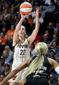 A woman is shooting the basketball in front of an audience.