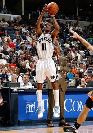 A man in white basketball uniform about to dunk.