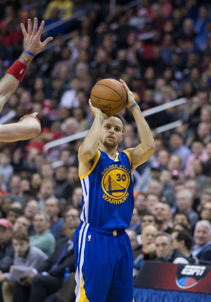 A man in blue and white basketball uniform holding a ball.