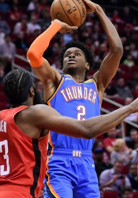 A basketball player is attempting to block the shot.