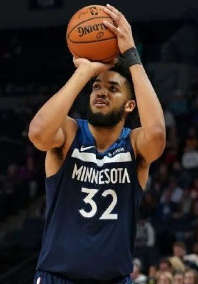 A man holding onto a basketball and wearing a minnesota timberwolves jersey.