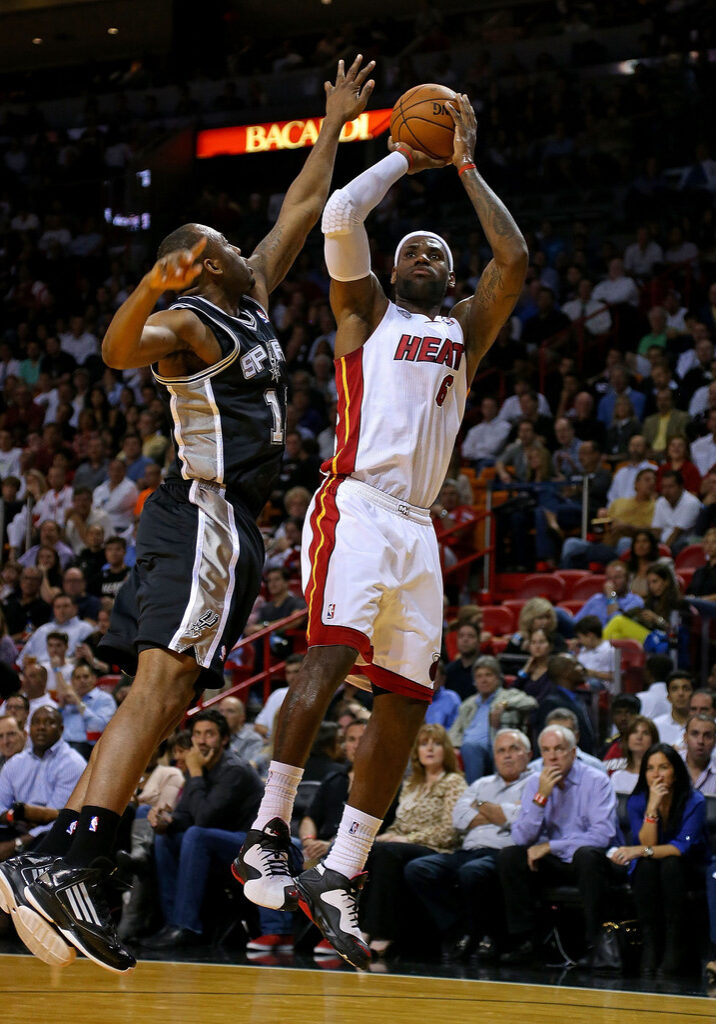 A couple of men playing basketball in front of an audience.