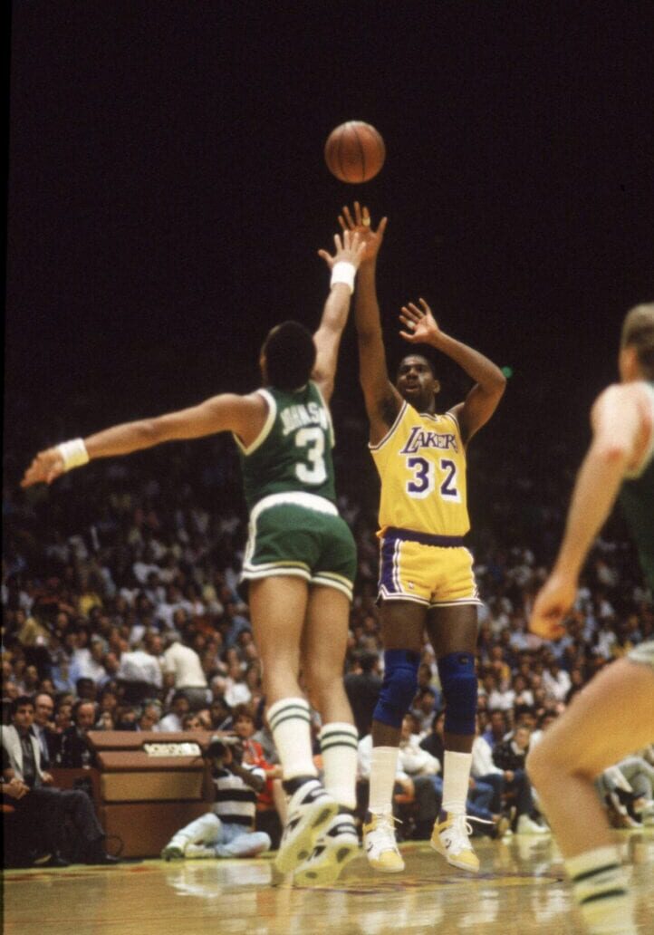 A couple of men playing basketball on a court.