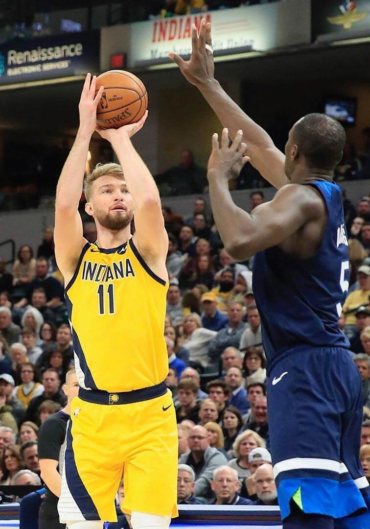 A man in yellow and blue basketball uniform holding a ball.